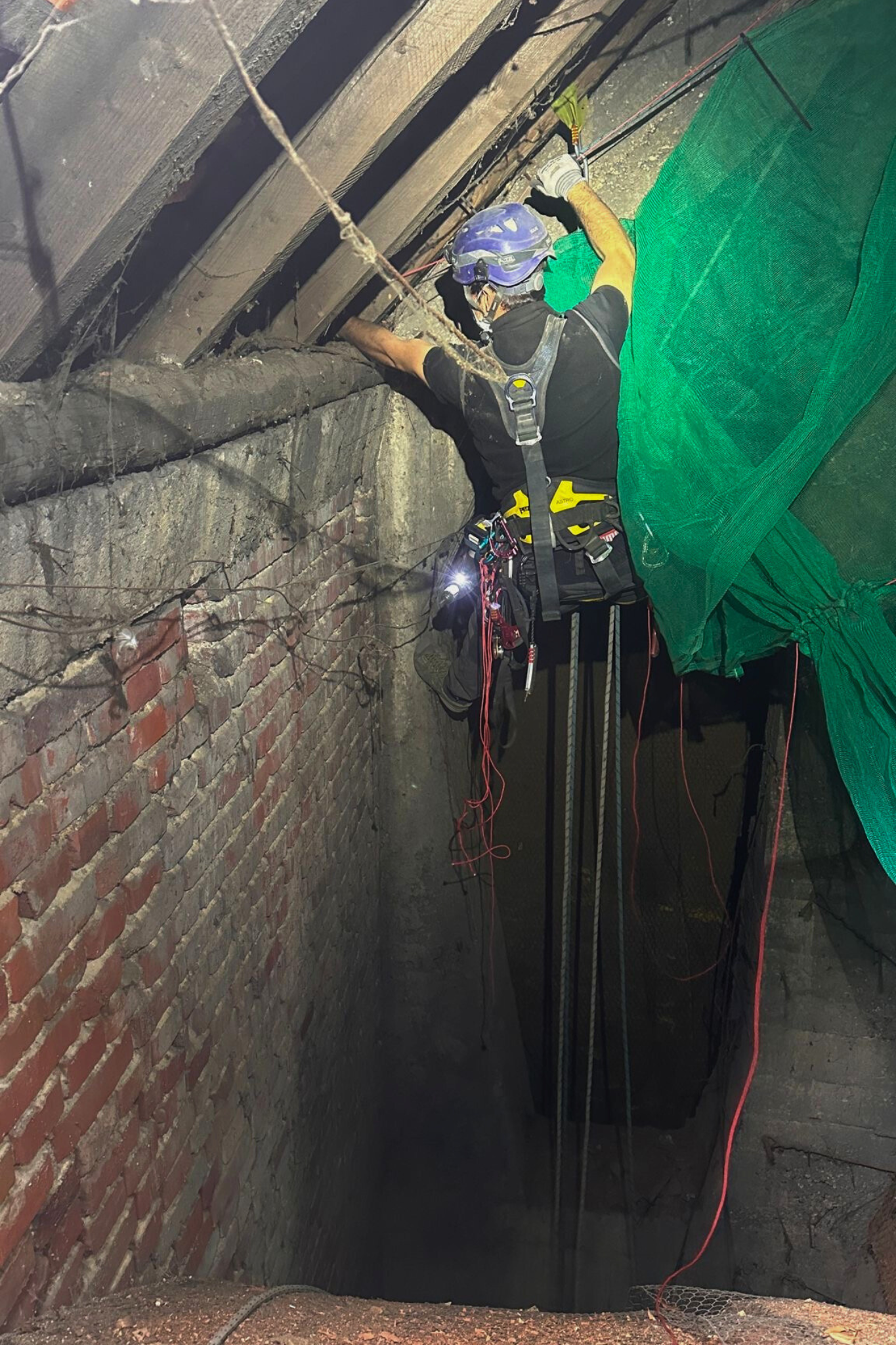 Industriekletterer bei der Installation eines Schutznetzes im schwer zugänglichen Dachbereich